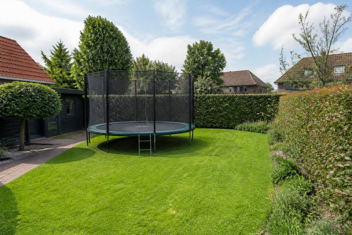 Ronde trampoline met veiligheidsnet in een achtertuin op gras