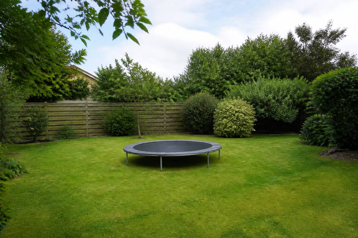 Middelgrote trampoline in een tuin met voldoende vrije ruimte rondom