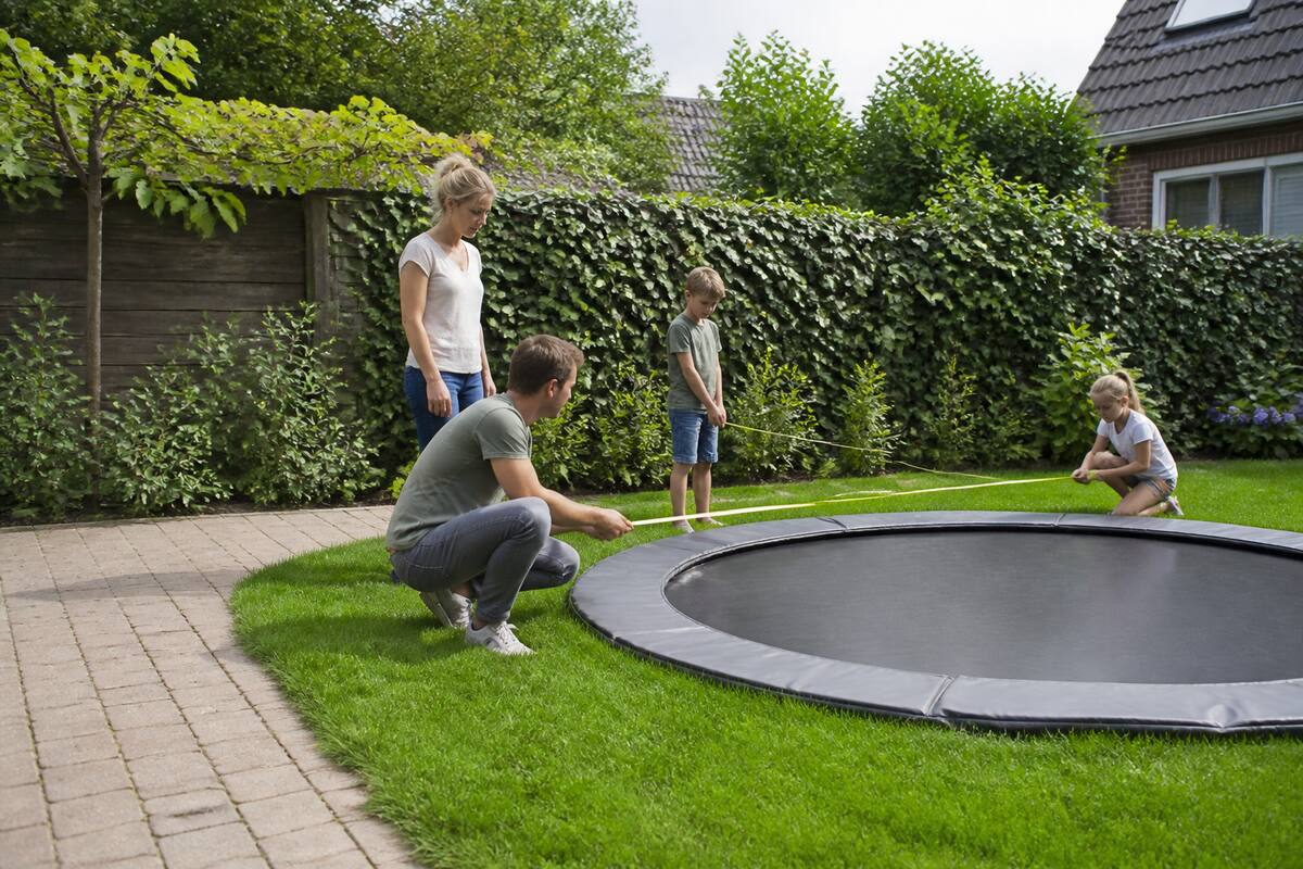 Gezin meet een plek in de tuin op voor het kopen van een trampoline
