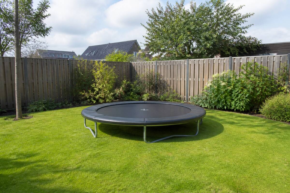 Middelgrote trampoline in een tuin met vrije ruimte rondom