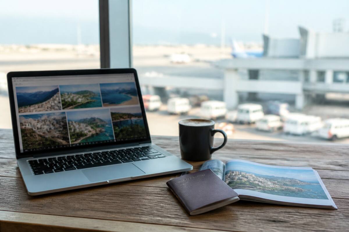 Reisgids en paspoort bij een laptop waarop vakanties worden vergeleken