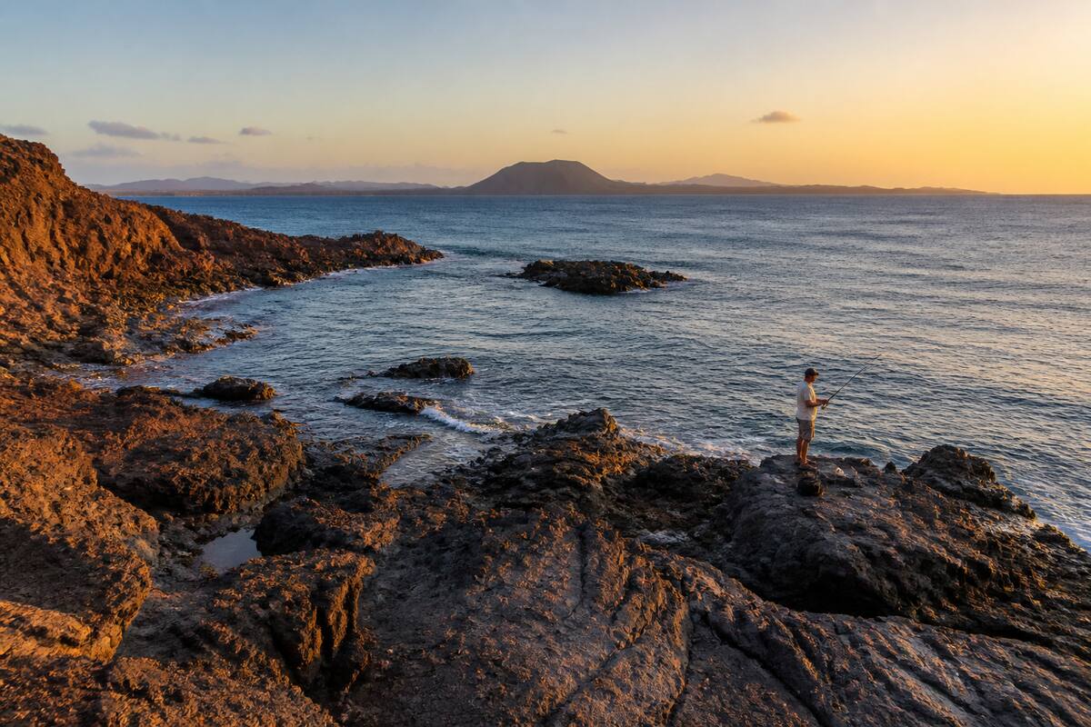 Visser aan de rotsachtige kust van Lanzarote met uitzicht op zee